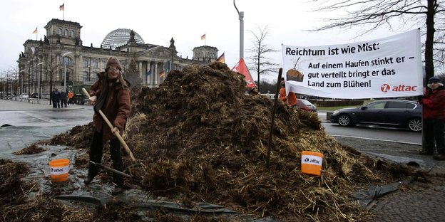 Misthaufen und "Reichtum ist wie Mist"-Banner vor dem Bundestag