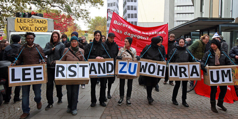 Demonstranten tragen ein Banner mit dem Slogan "Leerstand zu Wohnraum"