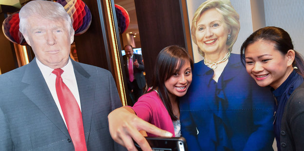 Zwei Lehrerinnen aus den USA fotografieren sich auf der Wahlparty des US-Generalkonsulates mit den Pappfiguren der Kandidaten Hillary Clinton und Donald Trump.