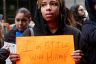 Eine junge, traurige Afroamerikanerin hält ein Schild mit der Aufschrift "I'm still with Hillary"
