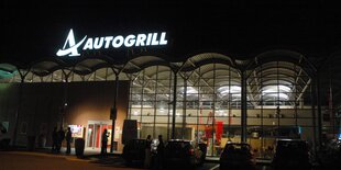 Eine Raststädt. Auf ihrem Dach leuchtet der Schriftzug „Autogrill“