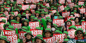 Südkoreaner mit grünen Hüten und Bannern bei einer Demonstration gegen Präsidentin Park