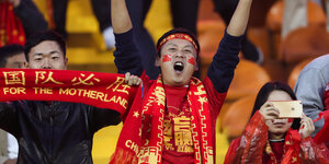 Drei Fans in traditionell chinesischer Kleidung im Fanblock