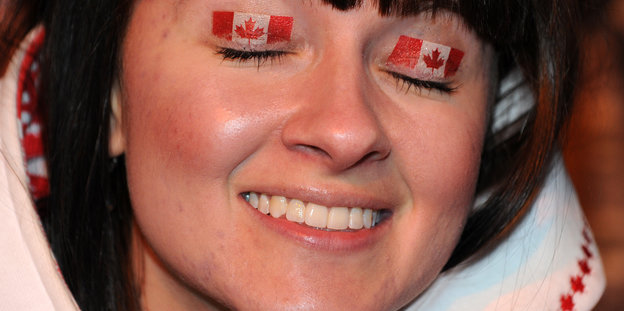 Eine Frau hat auf ihren geschlossenen Augenlidern die kanadische Nationalflagge aufgemalt