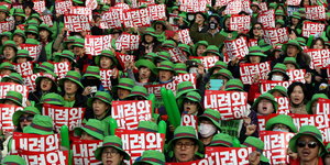 Menschen mit grünen Hüten halten identische Schilder hoch