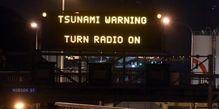 auf einem elektronisches Straßenschild steht „Tsunami Warning Turn Radio On“