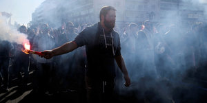 Demonstrant mit Feuerwerkskörper in Tränengaswolke