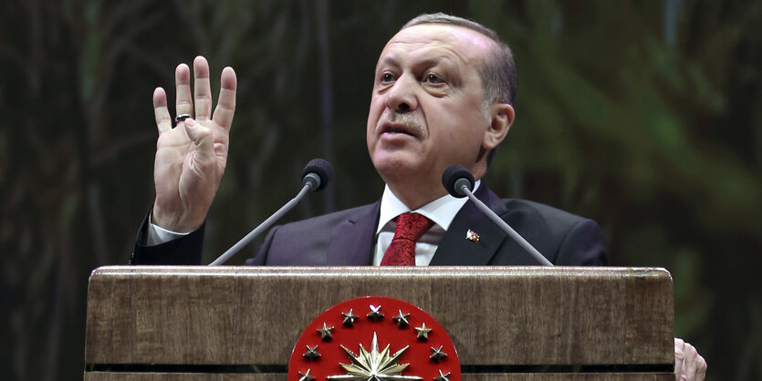 Erdogan mit erhobener Hand, hinter einem Pult bei einer Rede