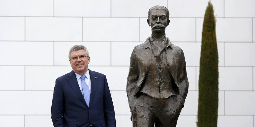 Thomas Bach steht neben Denkmal