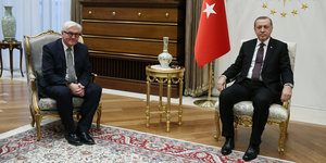 Steinmeier und Erdogan sitzen links und rechts von einem kleinen Tisch, im Hintergrund eine türkische Fahne