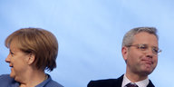 Zwei Menschen schauen aus dem Bild. Es sind Angela Merkel und Norbert Röttgen