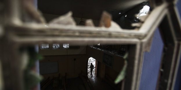 Blick durch ein zerstörtes Kirchenfenster auf einen Menschen