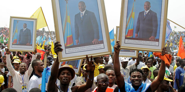 Menschen halten Portraits von Kongos Staatschef Kabila in die Höhe