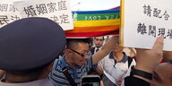 Ein Mann mit Regenbogenfahne gibt einem Polizisten und Demonstranten Kontra