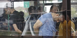 Männer in seltsamer Pose sitzen in einem Bus