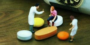 Miniaturarztfiguren stehen vor Tabletten