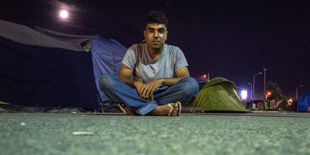 Flüchtling Abdulazez Dukhan sitzt auf dem Boden vor einem Zelt