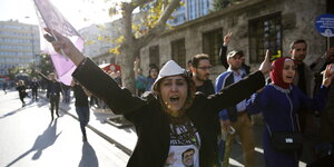 eine Frau ruft mit erhobenen Armen etwas auf einer Demonstration und schwenkt eine Fahne