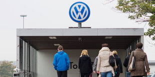 Menschen von hinten, sie gehen auf ein Volkswagen-Logo zu