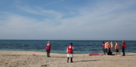 Mitarbeiter des roten Halbmondes mit der verdeckten Leiche eines ertrunkenen Flüchtlings am Strand