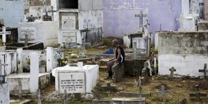Ein Mann sitzt am Allerseelen auf dem Friedhof in Santa Domingo