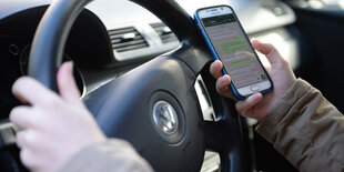 Eine Frau sitzt mit ihrem Handy in der Hand am Steuer