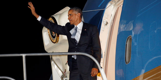 Barack Obama steht am oberen Ende einer Flugzeug-Gangway und winkt