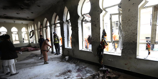 Menschen stehen im Inneren der durch den Anschlag zerstörten Moschee.