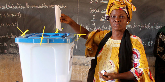 eine Frau wirft ihren Stimmzettel in eine Plastikwahlurne