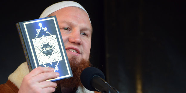 Islam-Prediger Pierre Vogel hält bei einer Kundgebung einen Koran hoch