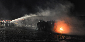 Polizisten versuchen, mit Wasserwerfern ein Feuer der Demonstranten zu löschen
