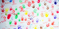 Bunte Abdrücke von Kinderhänden auf einer weißen Wand