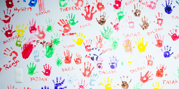 Bunte Abdrücke von Kinderhänden auf einer weißen Wand