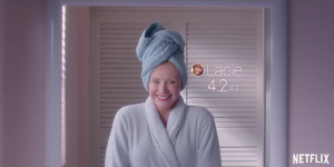 Eine Frau in Bademantel und mit Handtuch auf dem Kopf schaut in den Spiegel und freut sich über ihre 4,2-Bewertung