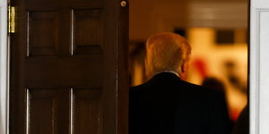 Donald Trumps Rücken durch eine halboffene Tür