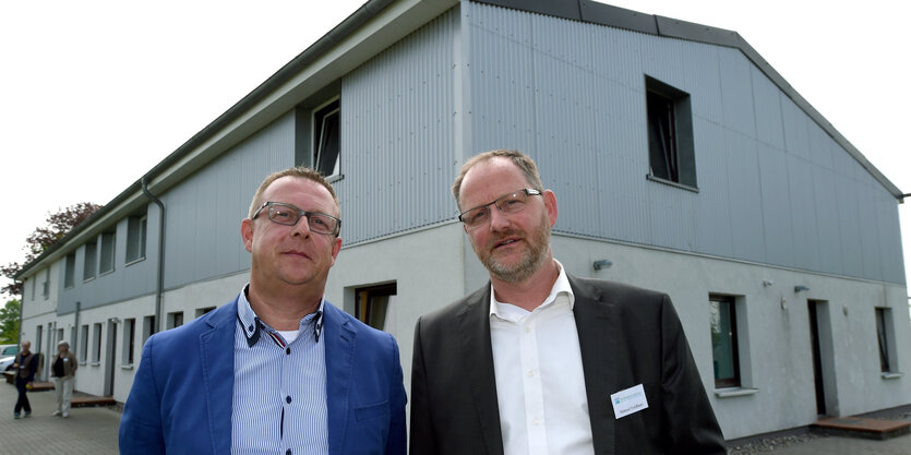 Zwei Männer stehen vor einem Haus aus Beton und Wellblech