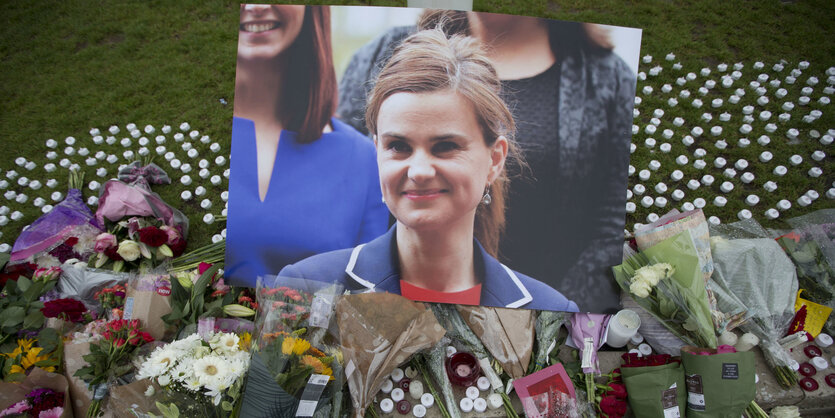 Ein großes Portraitbild zwischen Kerzen und Blumen