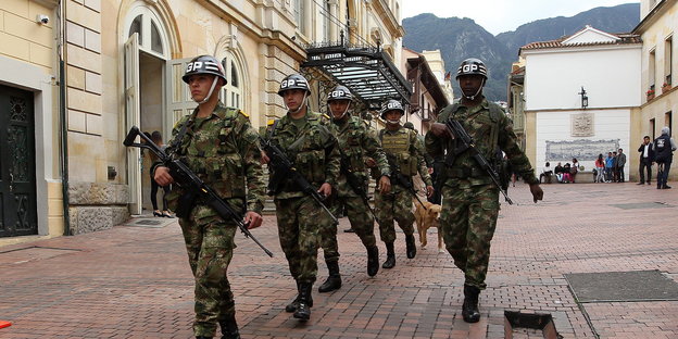 Bewaffnete Soldaten laufen eine Fußgängergasse entlang