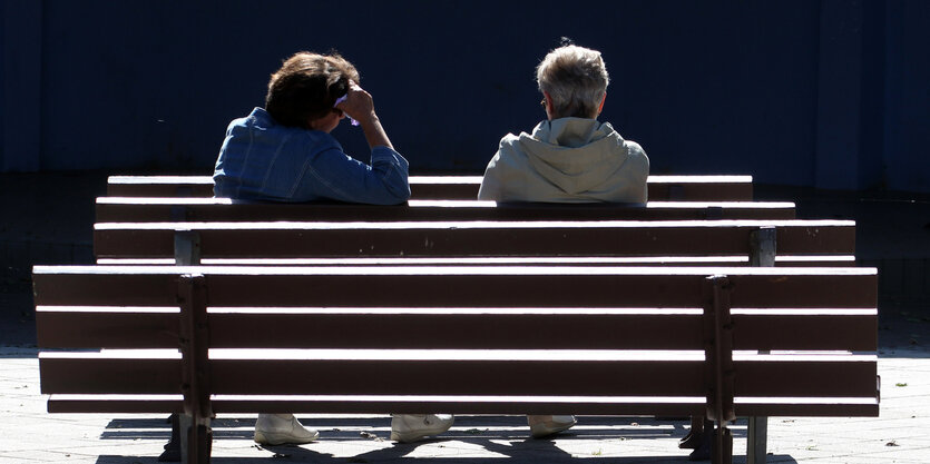 Zwei Menschen sitzen auf einer Bank