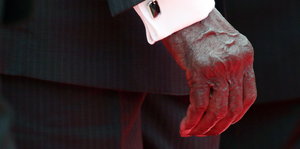 Robert Mugabes Hand, die aus dem Ärmel seines Anzugs ragt.