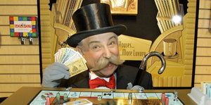 Ein Mann mit Frack und Schnurrbart, Zylinder und Spielgeld