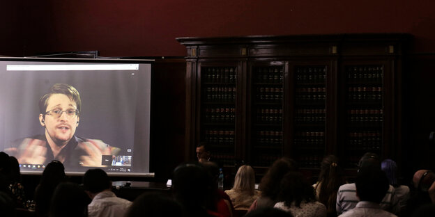 An der Universität in Buenos Aires schauen Teilnemende einer Konferenz auf einen Bildschrim, auf dem der Whistleblower Edward Snowden per Video zugeschaltet ist