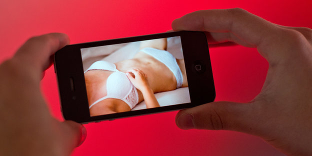 Ein Smartphone mit dem Bild eines Frauenkörpers in Unterwäsche