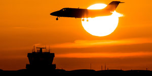 Ein Flugzeug landet im Sonnenuntergang auf der Landebahn des Flughafens in Düsseldorf