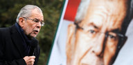 Der österreichische Präsidentschaftskandidat Alexander Van der Bellen steht neben einem Plakat mit seinem Gesicht und spricht in ein Mikrofon