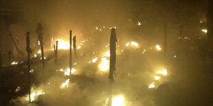 Aus Flammen in der Nacht ragen Zeltstangen hervor.