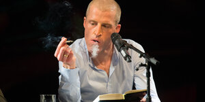 Der Autor Benjamin von Stuckrad-Barre raucht während einer Lesung