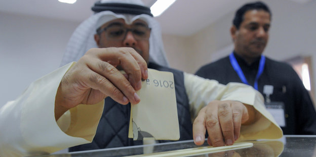 Ein Mann in Kuwait steckt einen Wahlzettel in eine Urne