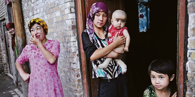 Uigurische Frauen mit Kindern vor einer Hauswand