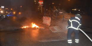 ein Feuerwehrmann löscht ein Feuer auf einer Straße